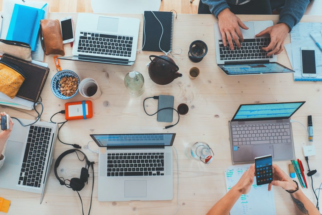 Group of people sit around a desk with computers, showing how often you should write new blog posts.